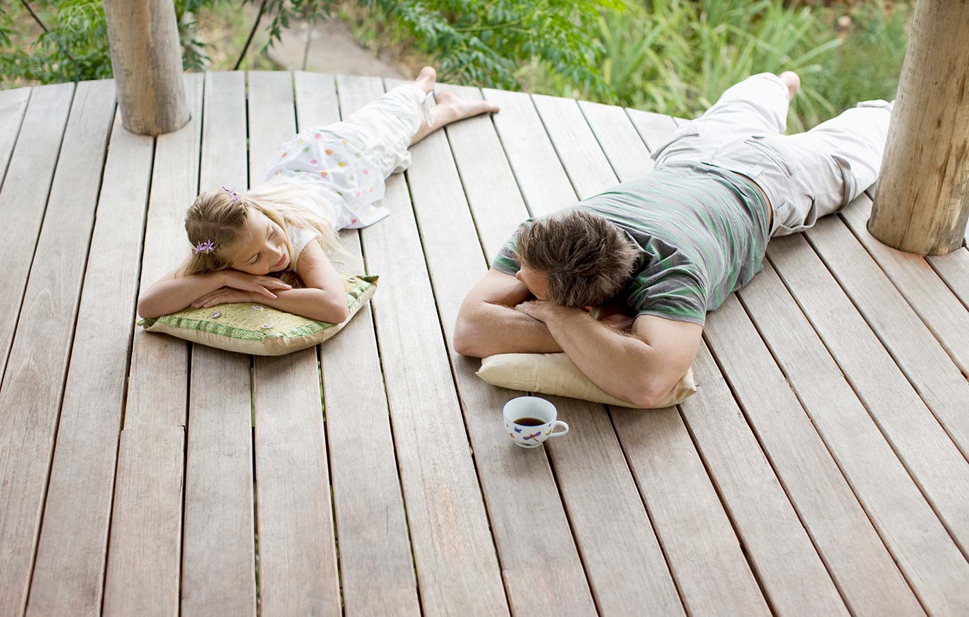 Vater und Tochter liegen auf einer Holz-Terrasse
